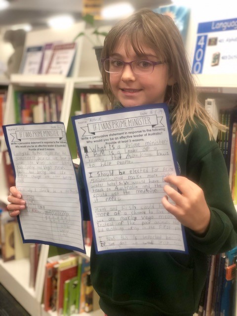 child displaying their writing book